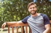 Young man relaxing on park bench on a summers day